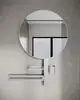 Runder Wandspiegel mit integriertem Ablage- und Halterungssystem in Silber, montiert auf einer hellen Wand. Produkt von Ideal Standard.